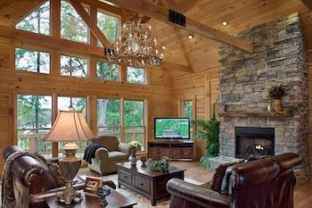 Photo of greatroom with geometric windows floor to ceiling, stone fireplace and exposed natural wood walls and ceiling