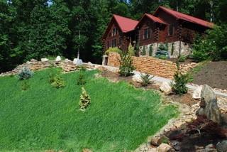 Photo of rear of a log home with three a-frame structures connected to form separate upper levels of the home.